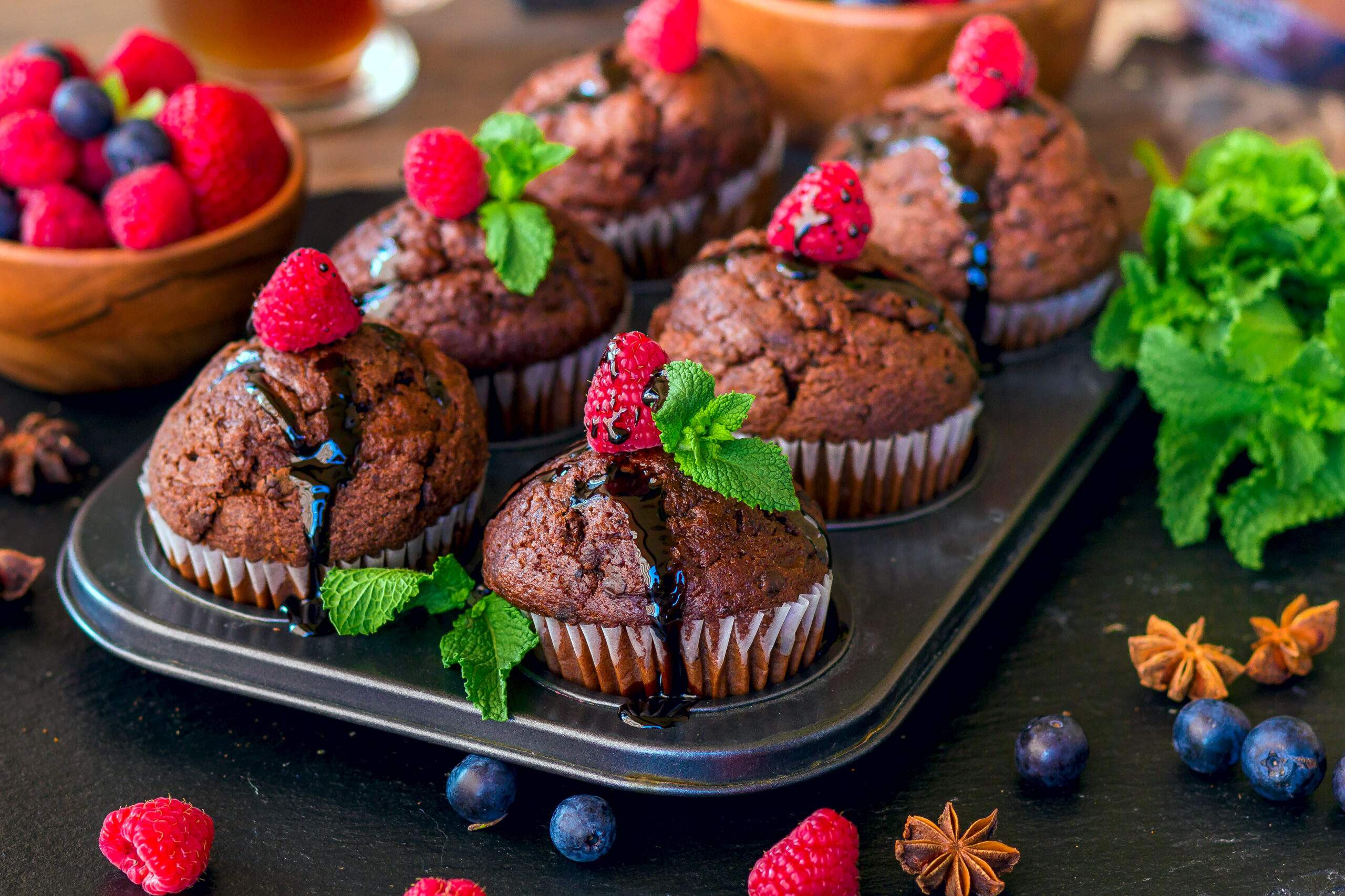 Chocolate,Muffins,With,Chocolate,Syrup,,Raspberries,And,Mint,In,A